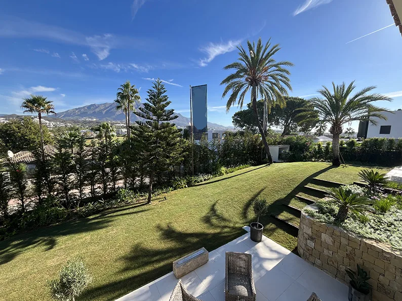 Jardín con césped, palmeras y vistas abiertas en Nueva Andalucía